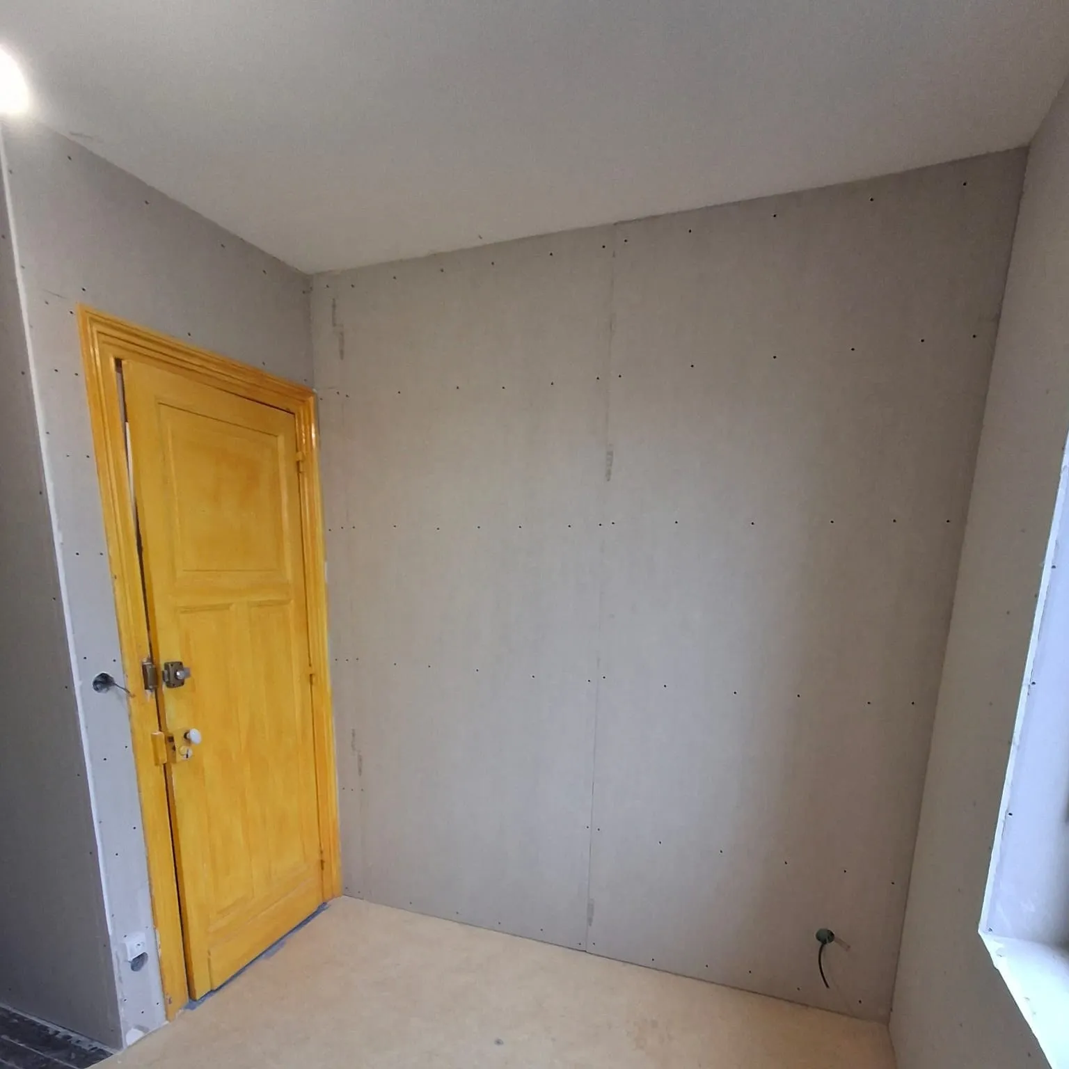 Chambre doublée en plaques de plâtre avec porte peinte en jaune, à Calais