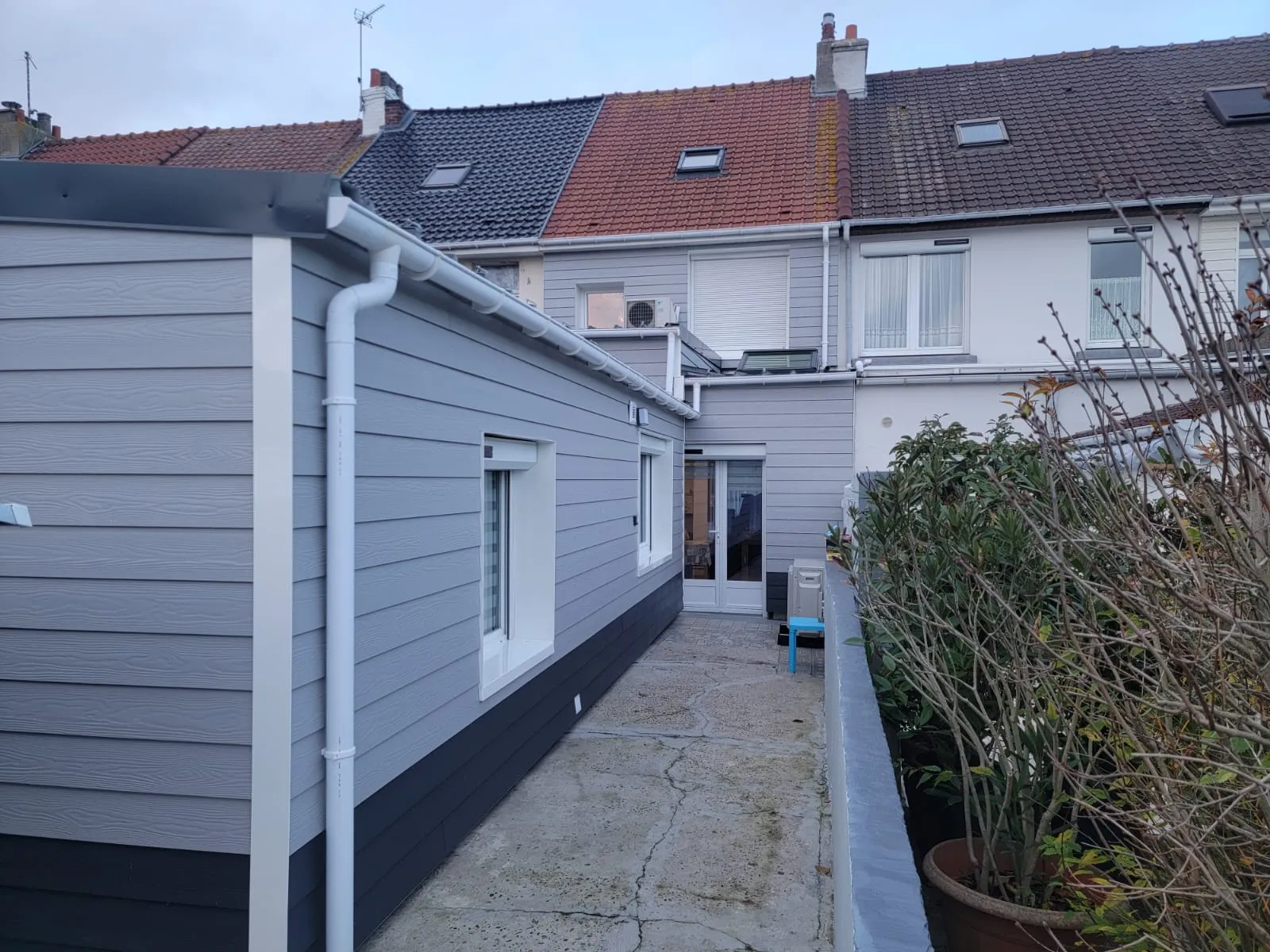 Façade arrière isolée et habillée d'un bardage Cedral gris clair, à Calais