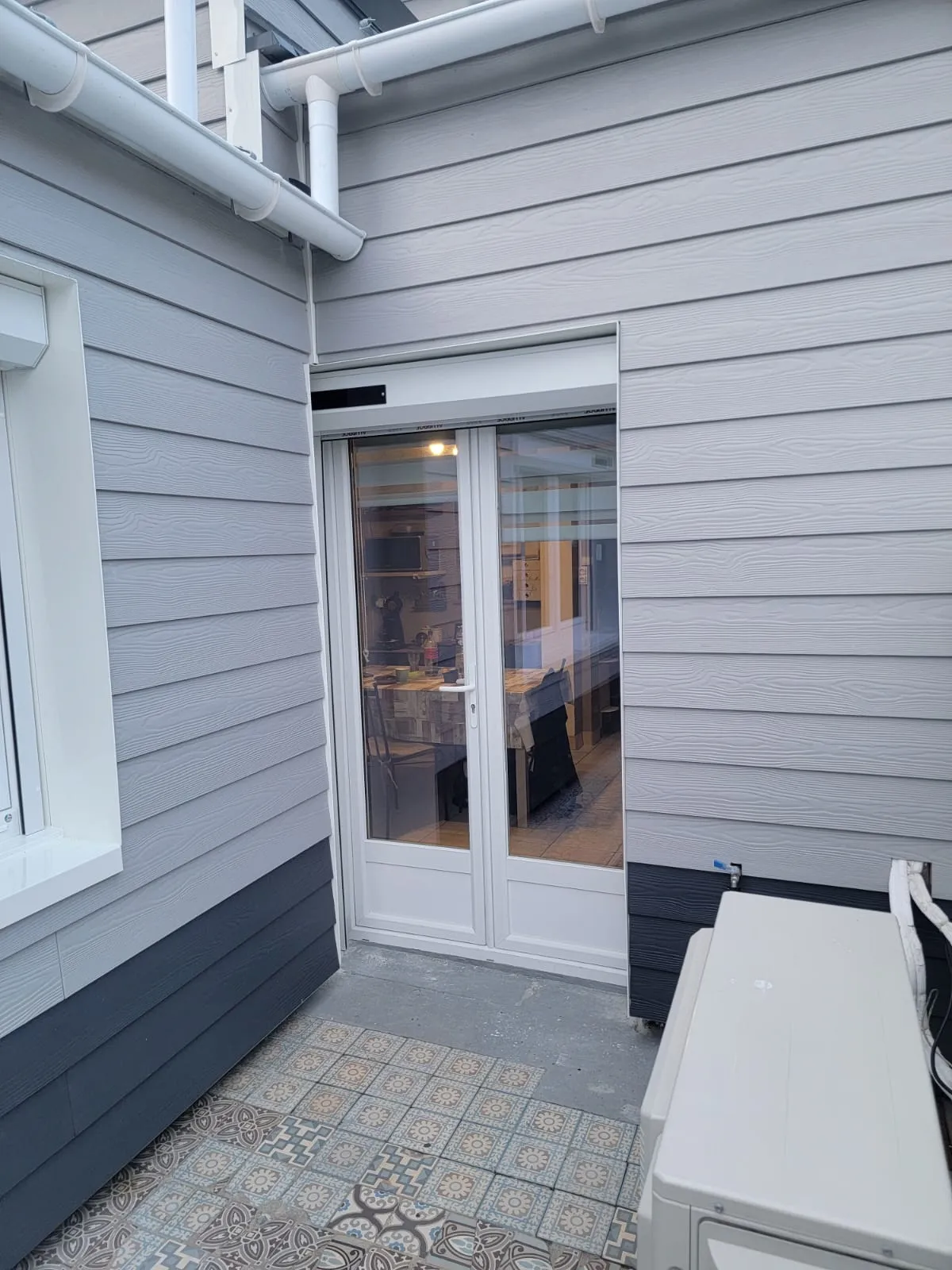 Porte-fenêtre neuve ouvrant sur la terrasse, bardage et soubassement sombre