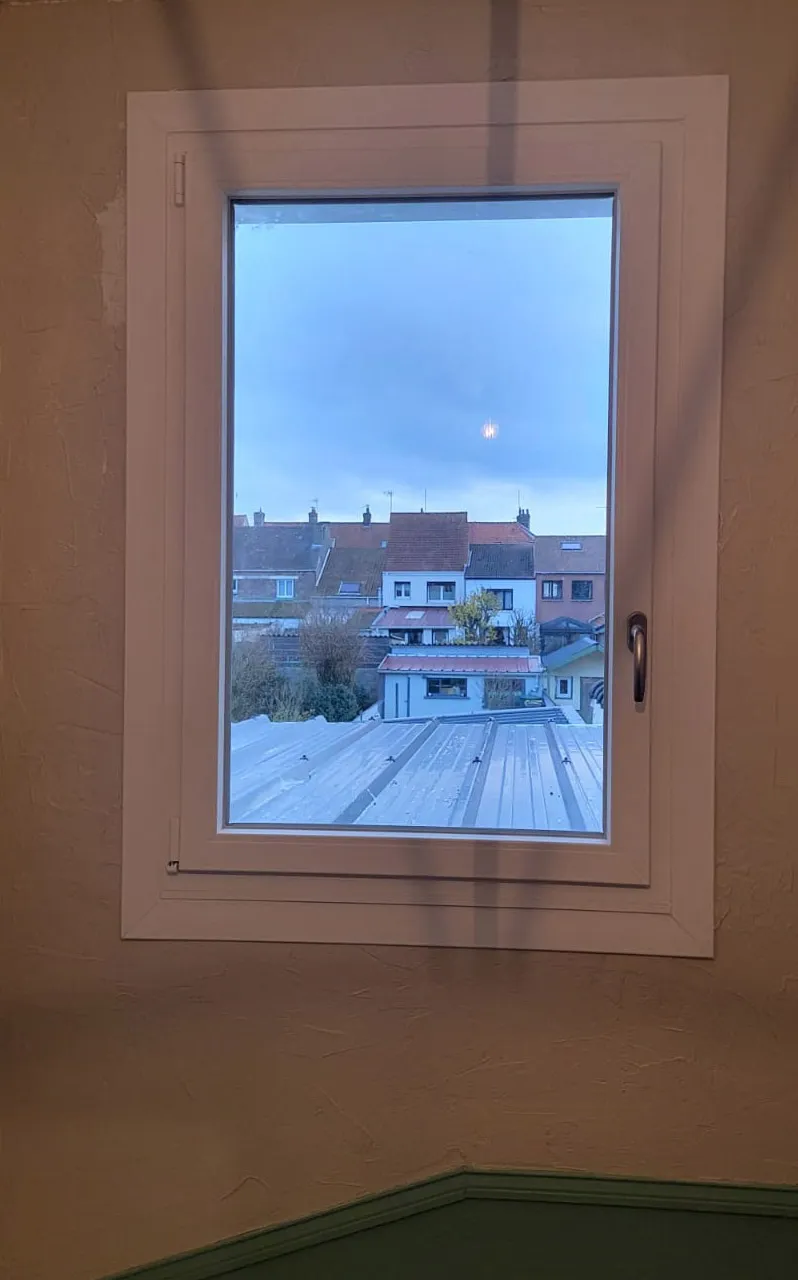 Vue depuis une fenêtre neuve sur la toiture en bac acier et les toits voisins