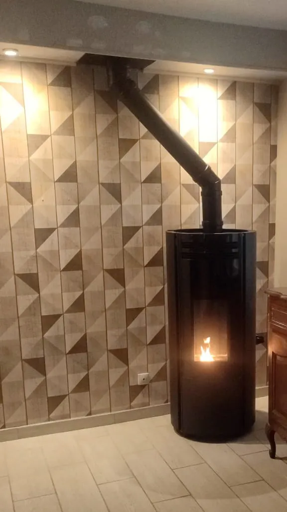 Poêle à granulés Thermorossi noir allumé devant un mur en carreaux géométriques, à Fouquereuil