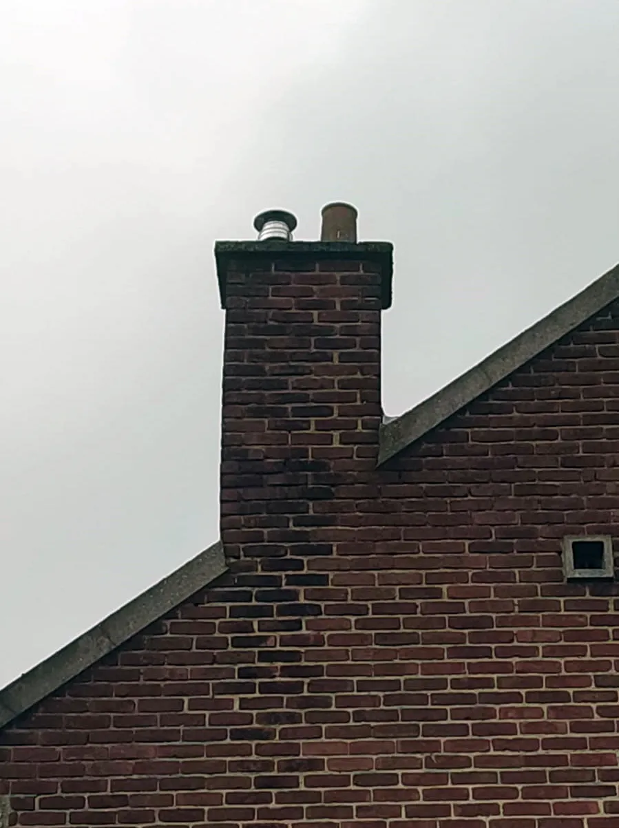 Sortie du conduit d'évacuation sur la cheminée en briques de la maison