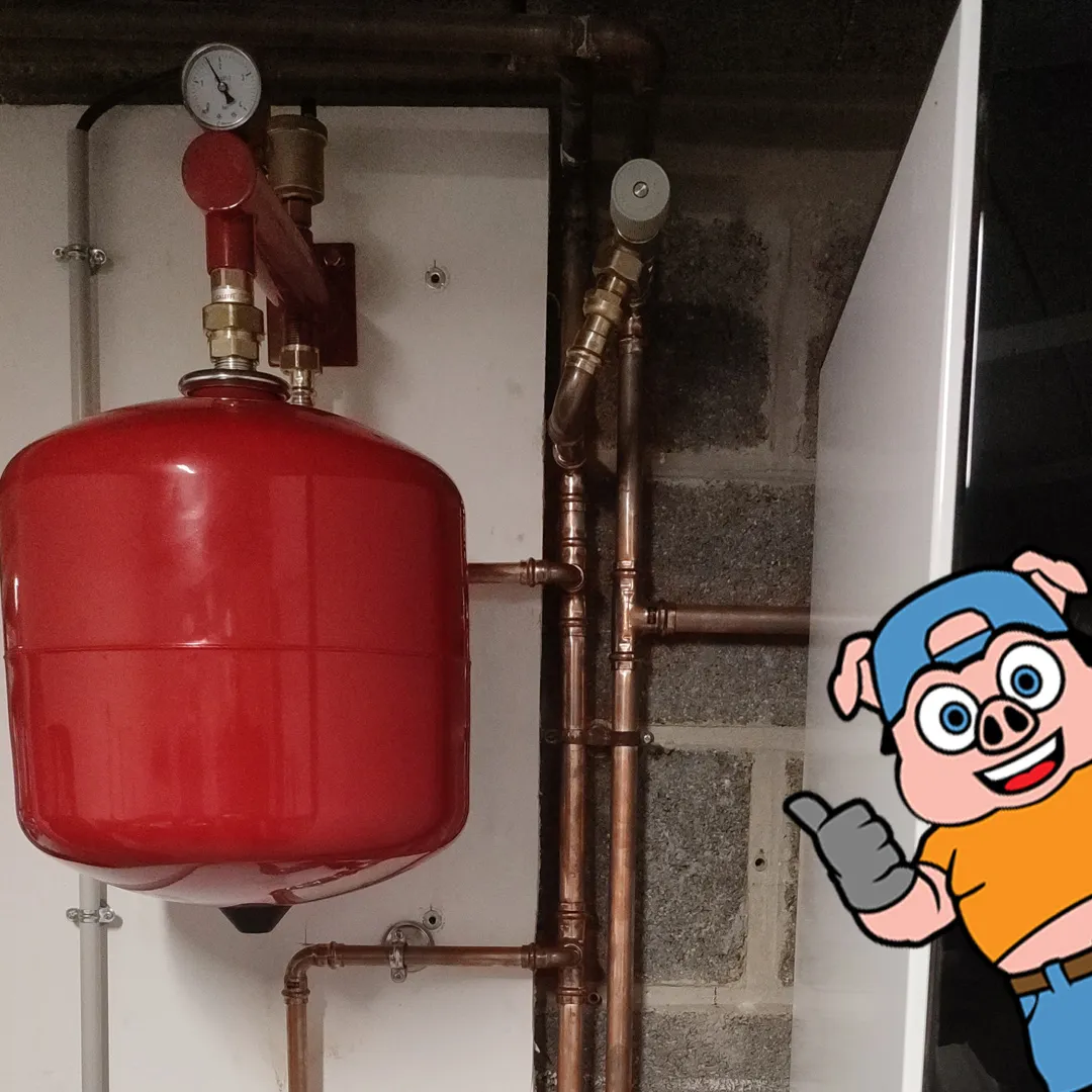 Vase d'expansion rouge et tuyauteries cuivre du réseau hydraulique neuf, avec la mascotte Kosto en illustration