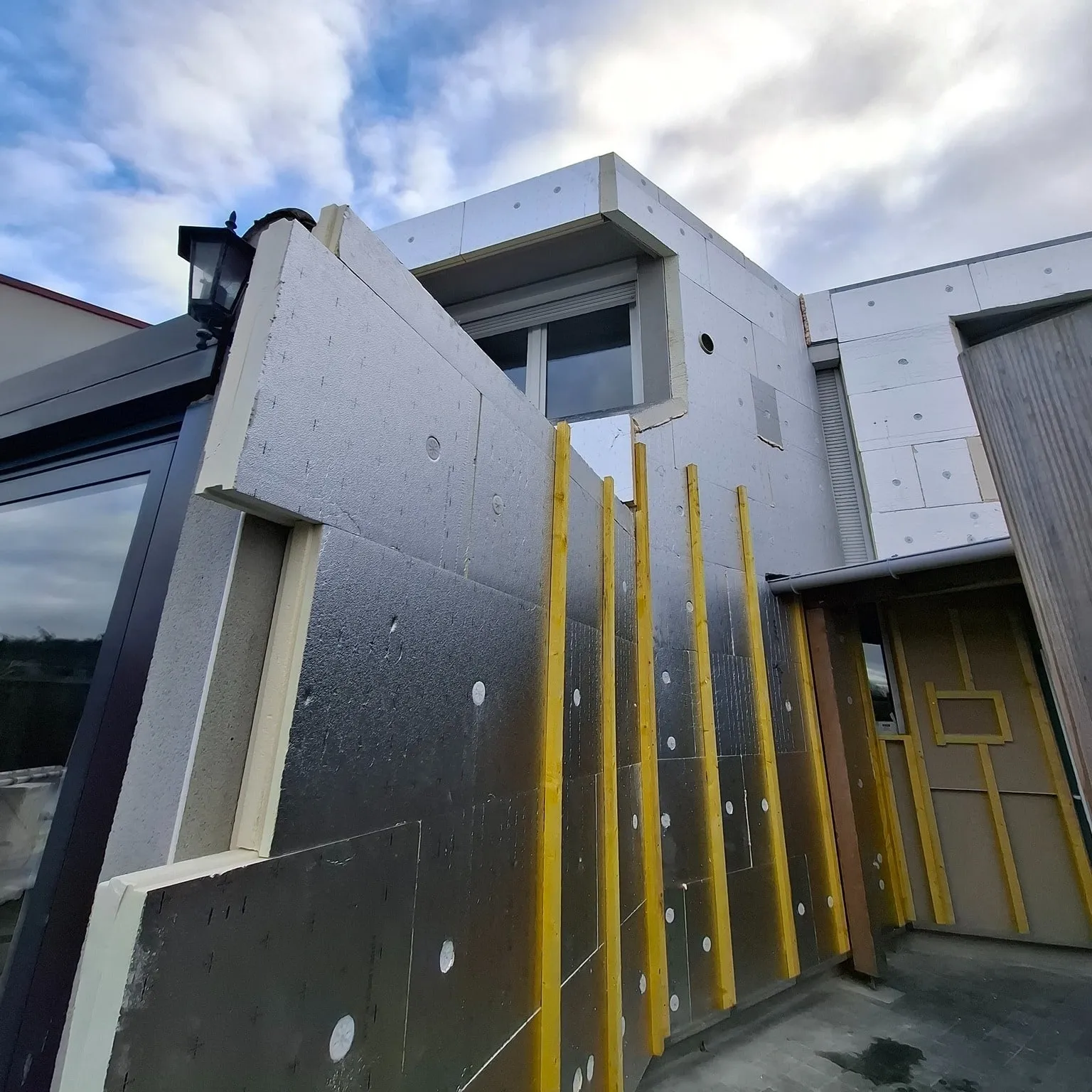 Panneaux isolants et tasseaux bois fixés sur la façade avant la pose du bardage, à Longuenesse