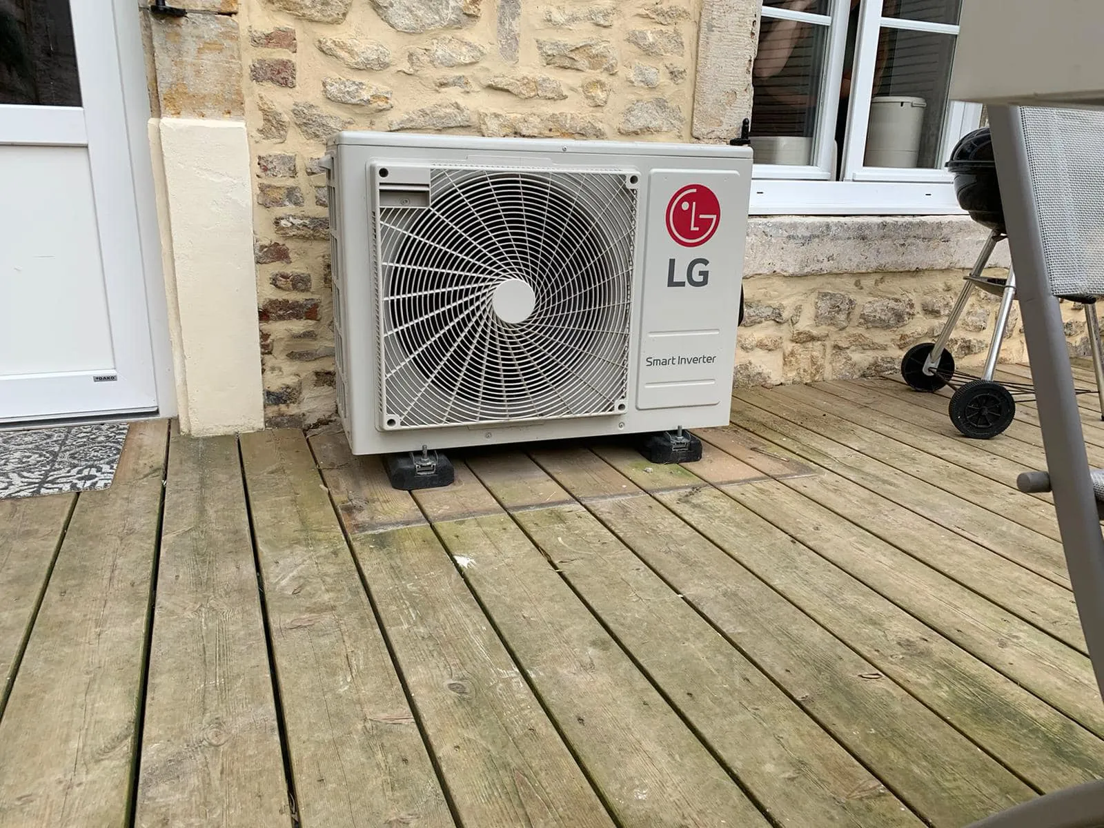 Unité extérieure LG de climatisation réversible posée sur la terrasse en bois du gîte, à Marquise
