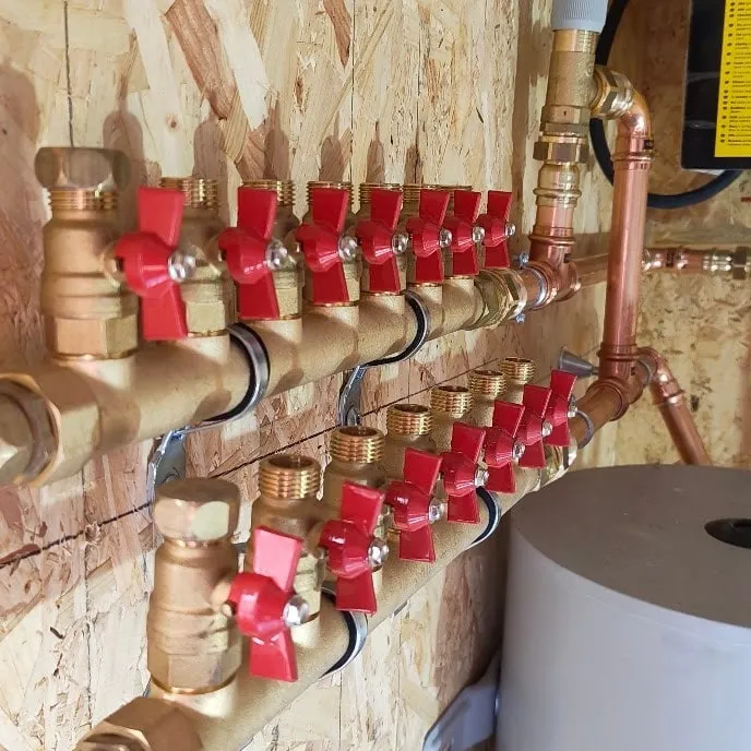 Collecteur de distribution en cuivre avec vannes rouges, réseau de chauffage neuf