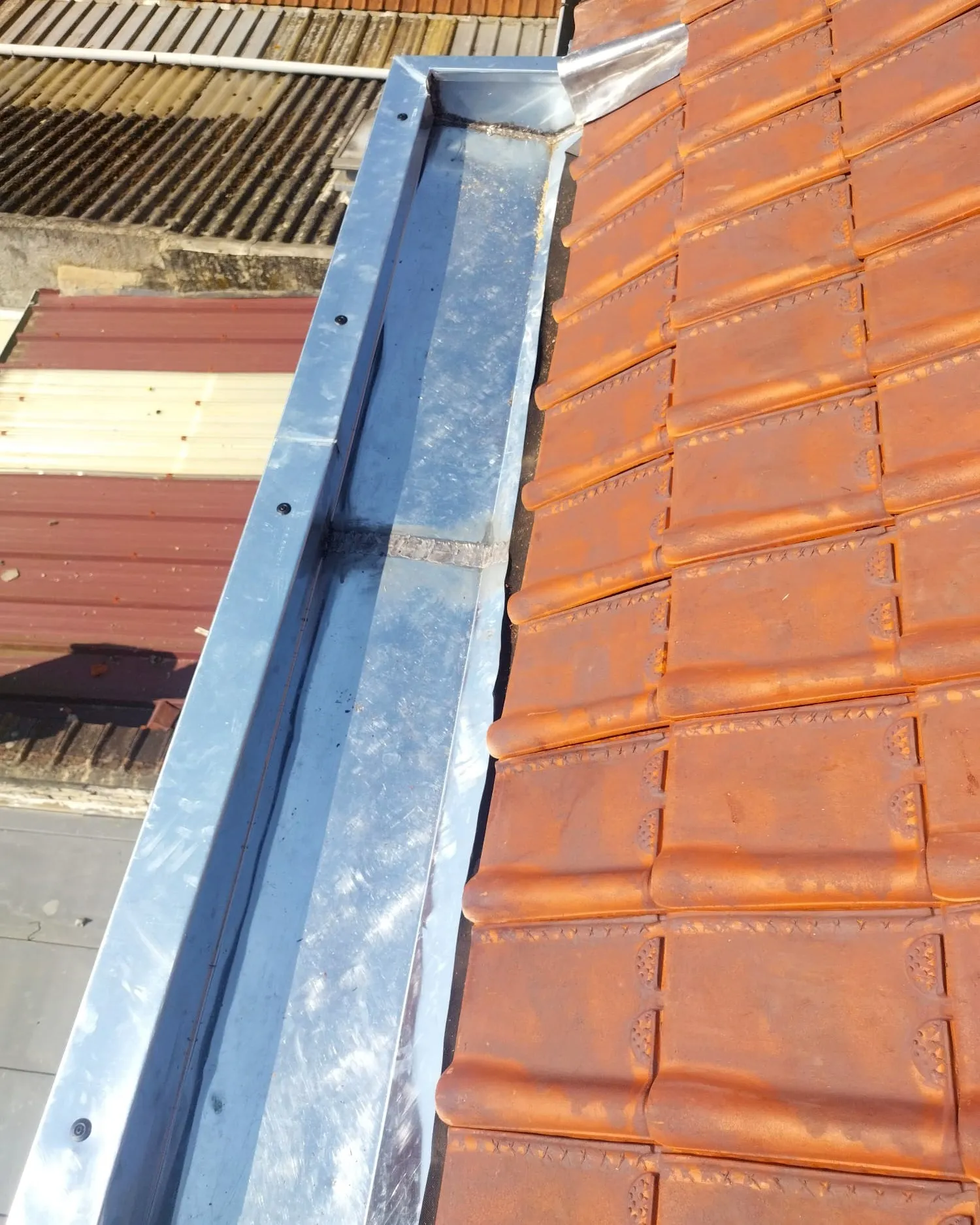 Détail du chéneau en zinc soudé et de la rive en tuiles