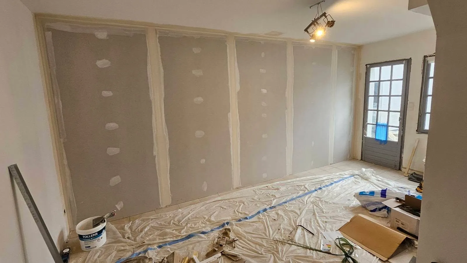 Mur doublé en plaques de plâtre avec bandes et joints, sol protégé