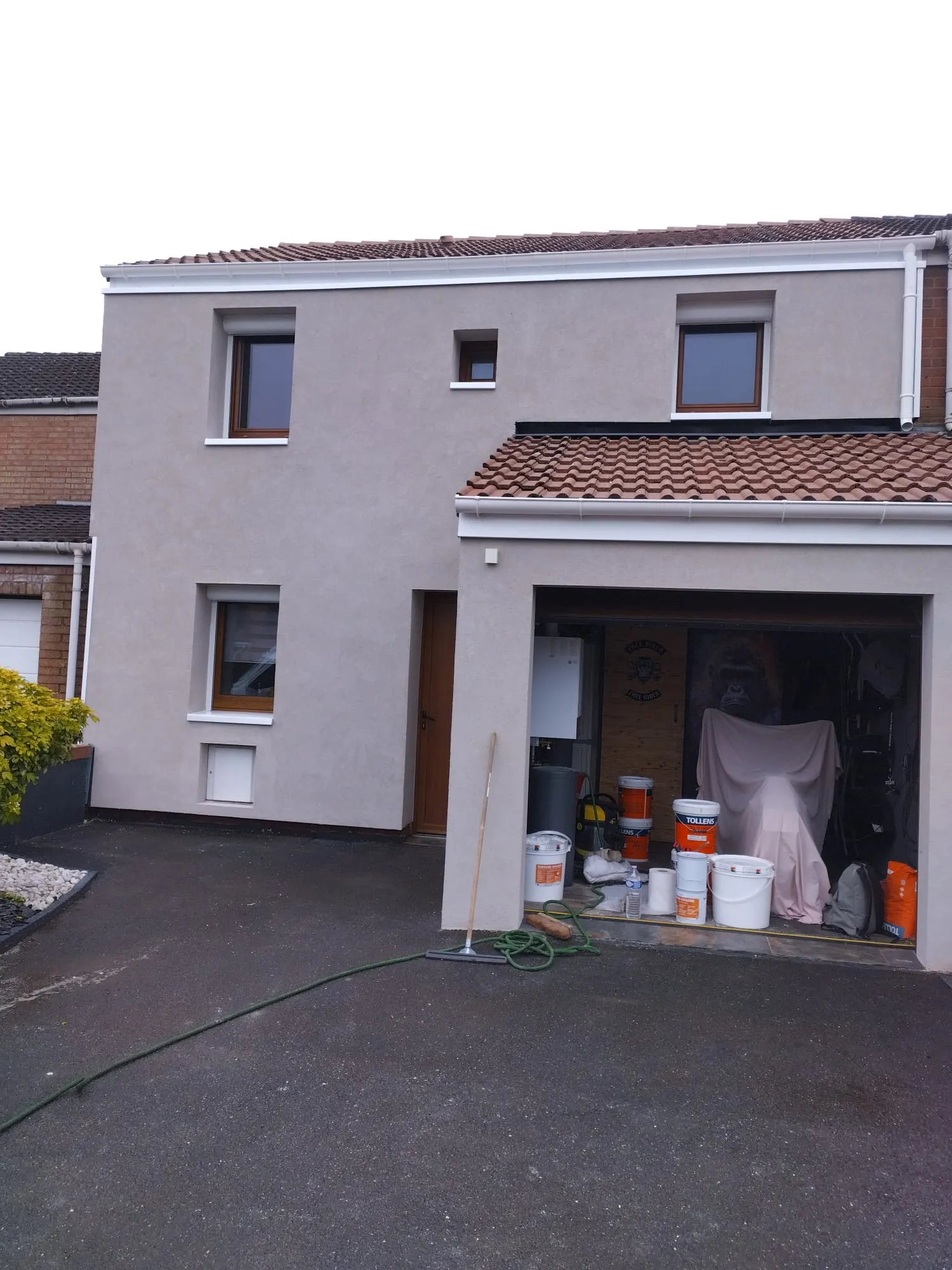 Façade avant de la maison après isolation par l'extérieur et enduit, toiture en tuiles traitée