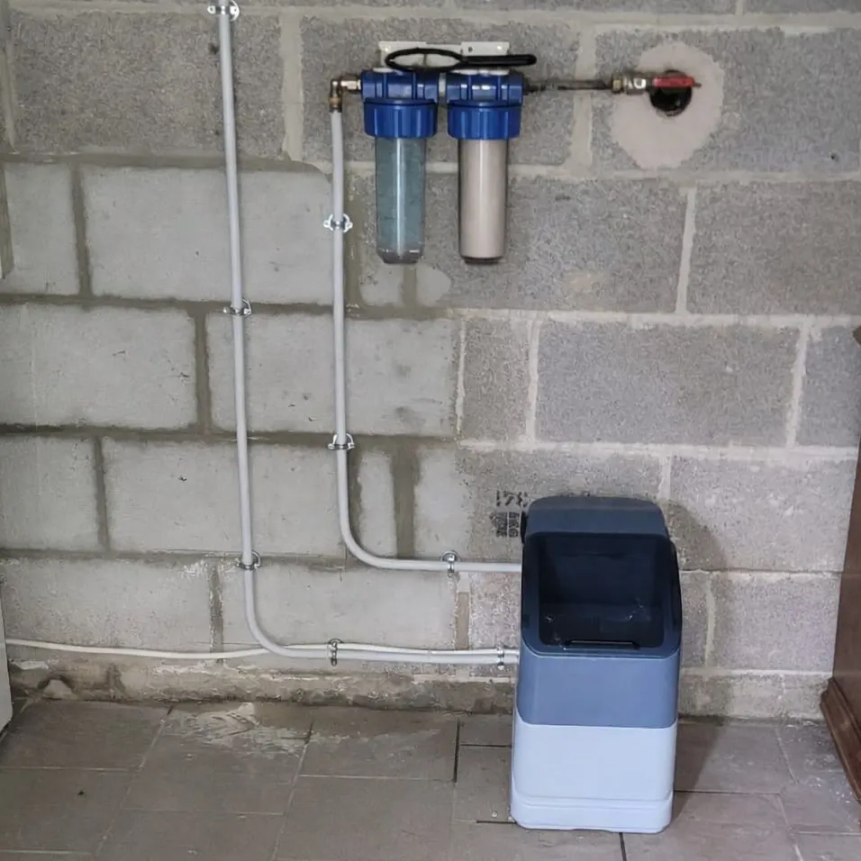 Adoucisseur d'eau et double filtre à cartouches posés sur un mur de parpaings, à Zutkerque